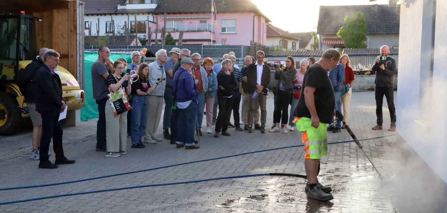 Die Teilnehmer schauen zu, wie die Pflasterfläche über einem Nest mit dem Heißwassergerät behandelt wird
